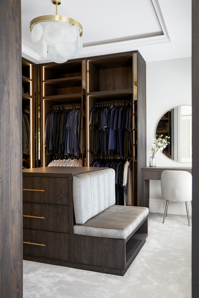 Design ideas for an expansive modern gender-neutral dressing room in Hertfordshire with open cabinets, dark wood cabinets, carpet, grey floor and coffered.