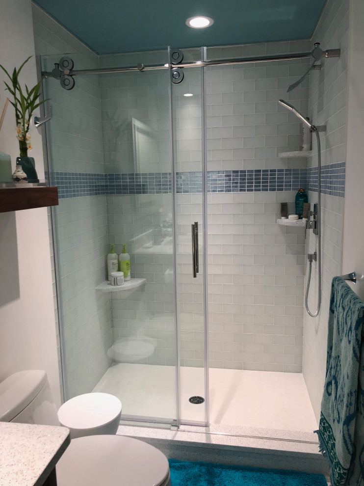 Photo of a mid-sized modern 3/4 bathroom in Bridgeport with flat-panel cabinets, brown cabinets, an alcove shower, a one-piece toilet, blue tile, glass tile, white walls, porcelain floors, an undermount sink, engineered quartz benchtops, white floor, a sliding shower screen and white benchtops.