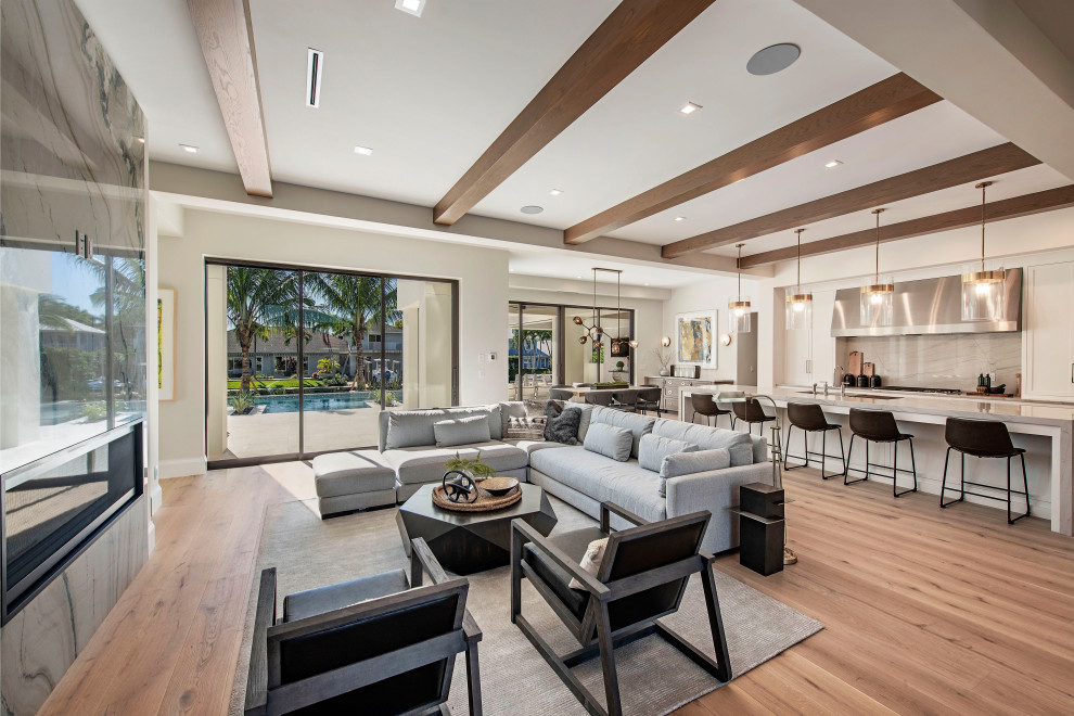 Expansive beach style open concept living room in Other with medium hardwood floors, a ribbon fireplace, a concealed tv, brown floor and exposed beam.