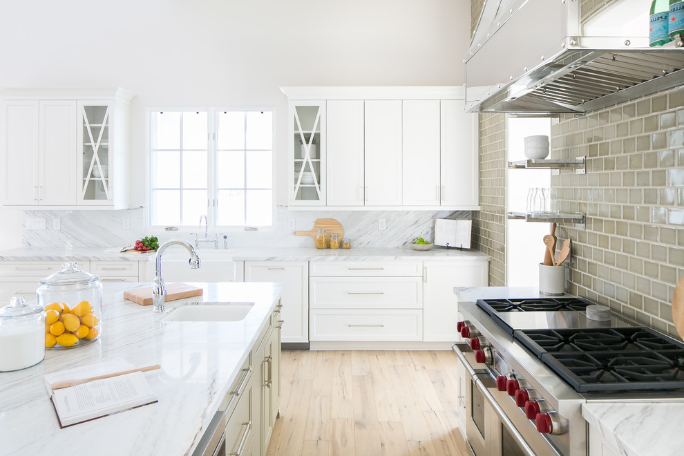 Large transitional light wood floor and brown floor eat-in kitchen photo in Phoenix with a farmhouse sink, white cabinets, marble countertops, green backsplash, ceramic backsplash, stainless steel appliances and two islands