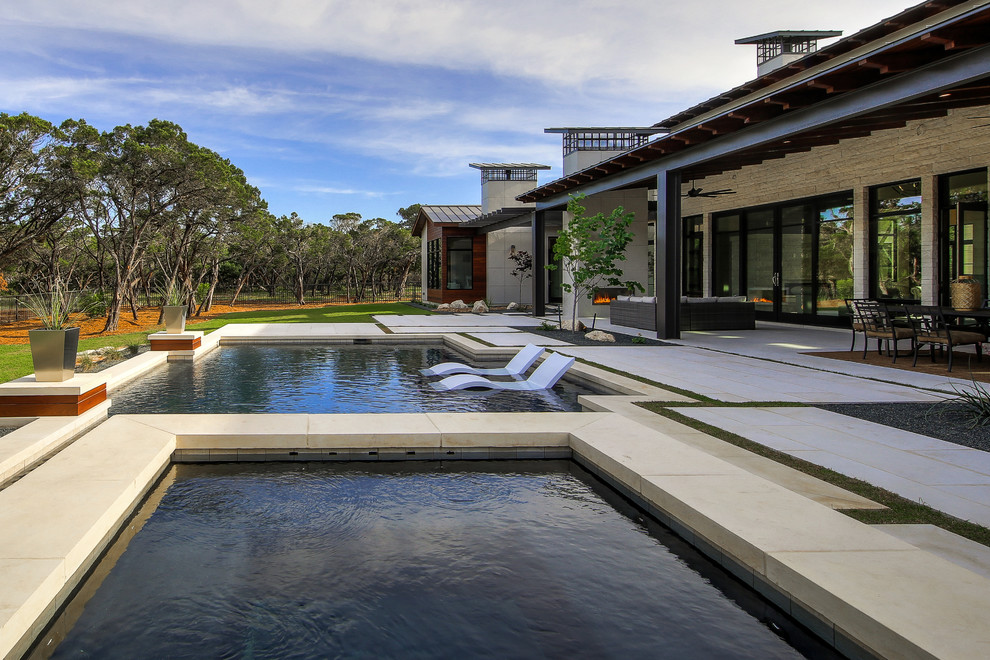 Photo of a large transitional backyard rectangular natural pool in Austin with a pool house and natural stone pavers.