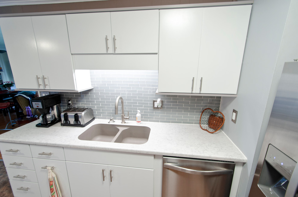 Example of a small minimalist galley vinyl floor and brown floor eat-in kitchen design in Chicago with an integrated sink, flat-panel cabinets, gray cabinets, laminate countertops, gray backsplash, glass tile backsplash, stainless steel appliances and no island