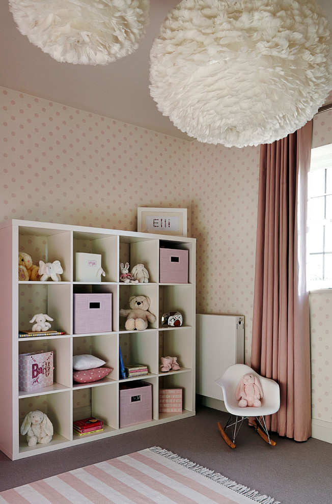 Design ideas for a transitional nursery for girls in London with beige walls, carpet and grey floor.