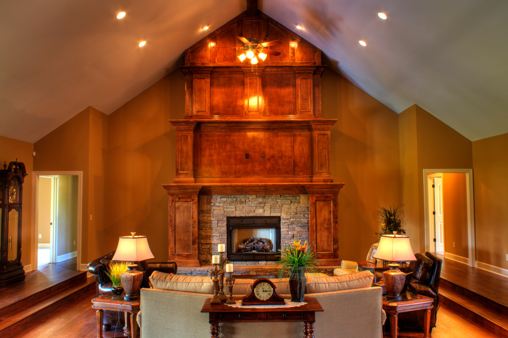 This is an example of a large traditional formal open concept living room in Other with a wall-mounted tv, brown walls, medium hardwood floors, a standard fireplace and a stone fireplace surround.