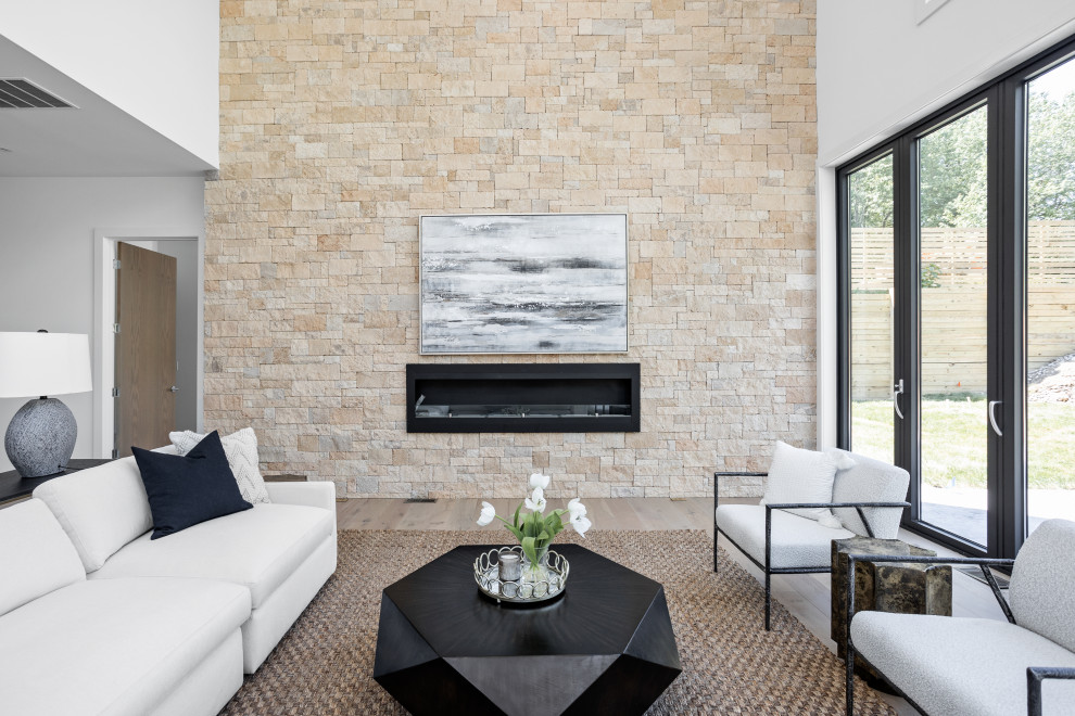 Cette image montre une très grande salle de séjour minimaliste ouverte avec un mur blanc, parquet clair, cheminée suspendue, un manteau de cheminée en pierre de parement et un sol multicolore.