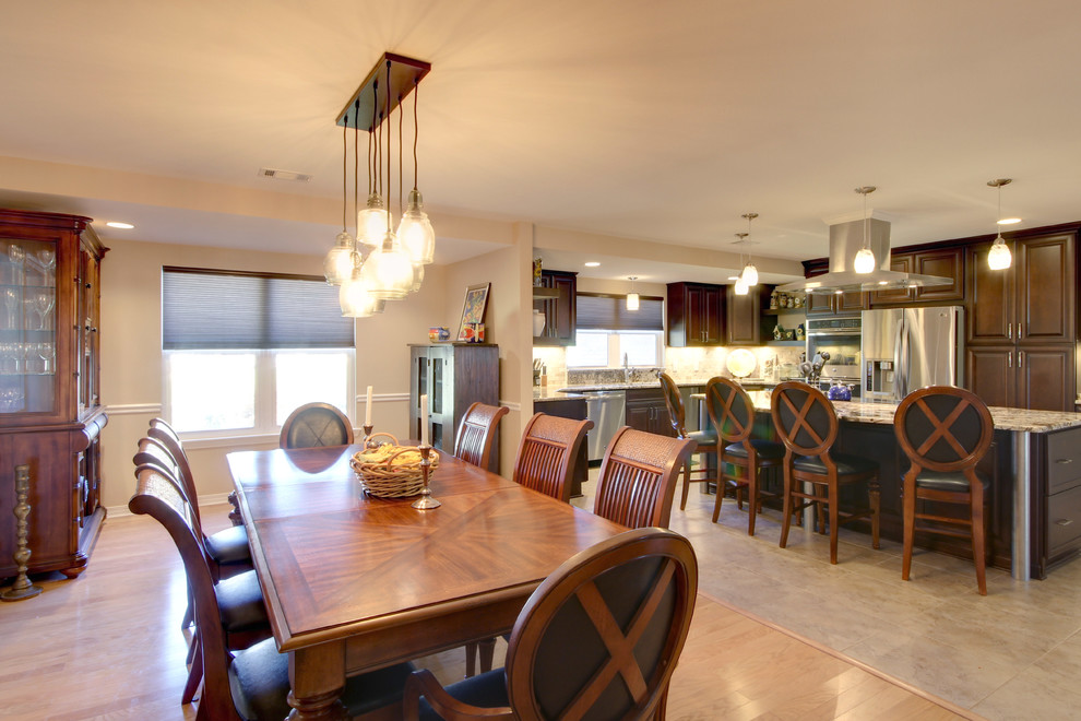 Eat-in kitchen - large transitional l-shaped porcelain tile eat-in kitchen idea in Miami with an undermount sink, raised-panel cabinets, dark wood cabinets, granite countertops, beige backsplash, stone tile backsplash, stainless steel appliances and an island