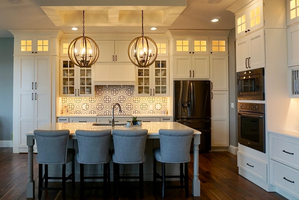 Large transitional l-shaped medium tone wood floor kitchen pantry photo in Cedar Rapids with an undermount sink, shaker cabinets, white cabinets, quartz countertops, multicolored backsplash, cement tile backsplash, stainless steel appliances and an island