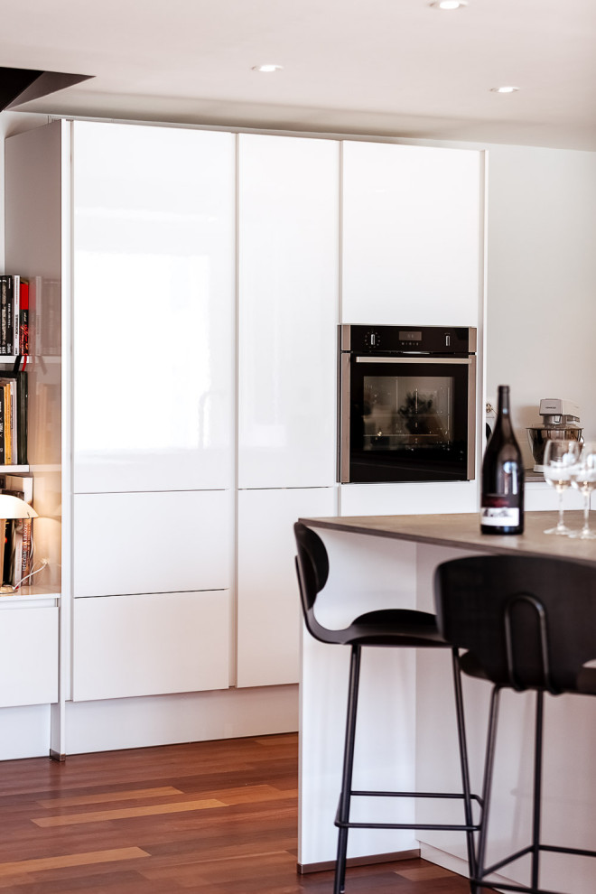 Immagine di una grande cucina minimalista con lavello a vasca singola, paraspruzzi bianco, elettrodomestici bianchi, pavimento marrone e top grigio