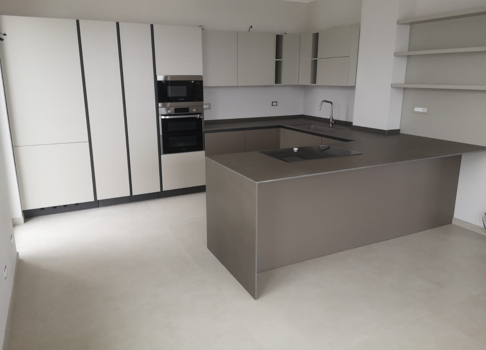 Cucina Laccato Opaco color Mandorla per colonne e pensili e color Caffelatte per le basi. Maniglia a gola e zoccolo Brunito. Top in Neolith Barro Satinato con lavello sottotop in Granitek Tortora. Pa