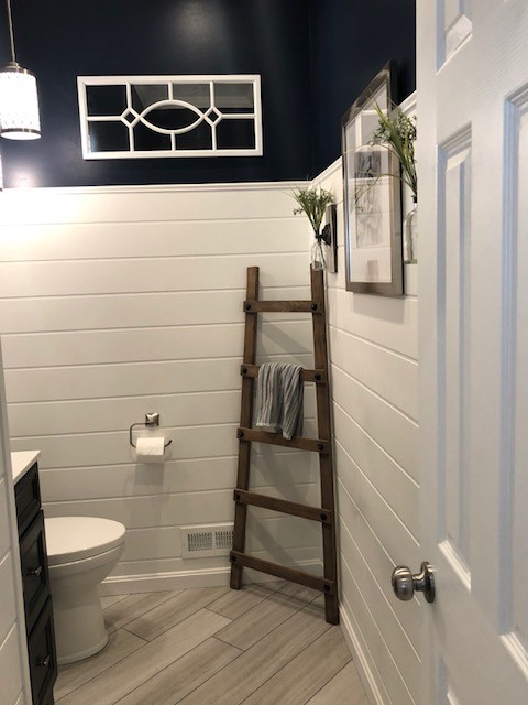 This is an example of a mid-sized transitional 3/4 bathroom in DC Metro with recessed-panel cabinets, black cabinets, a two-piece toilet, blue walls, porcelain floors, an undermount sink, engineered quartz benchtops, beige floor and white benchtops.