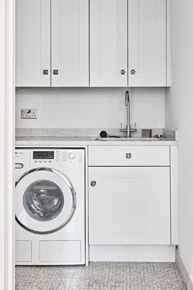 This is an example of a small transitional laundry room in London with an undermount sink and shaker cabinets.