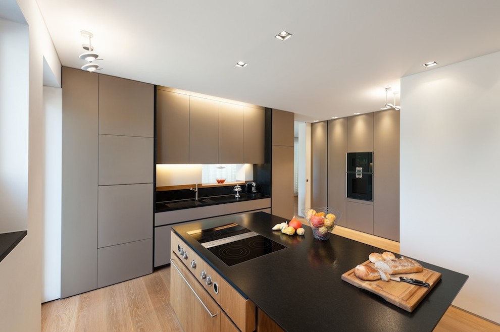 Inspiration for a large modern separate kitchen in Munich with an integrated sink, flat-panel cabinets, grey cabinets, panelled appliances, medium hardwood floors and with island.