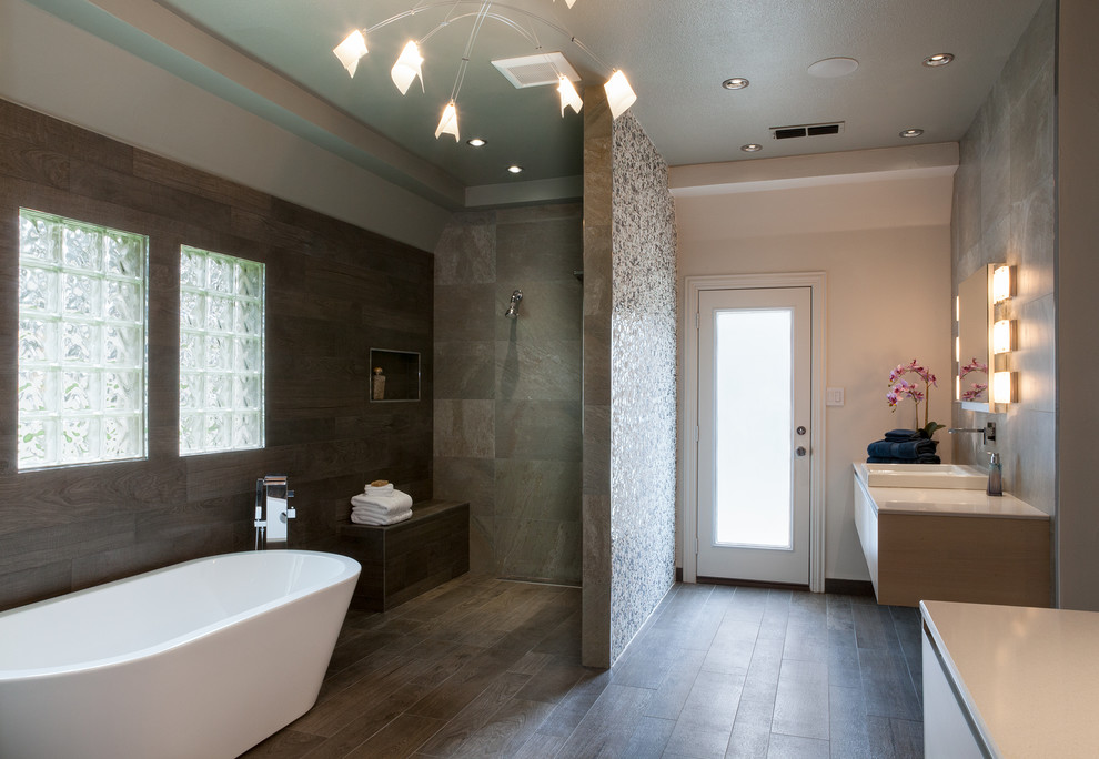Photo of a mid-sized contemporary master bathroom in Dallas with flat-panel cabinets, white cabinets, a freestanding tub, an open shower, gray tile, slate, grey walls, dark hardwood floors, a drop-in sink and solid surface benchtops.