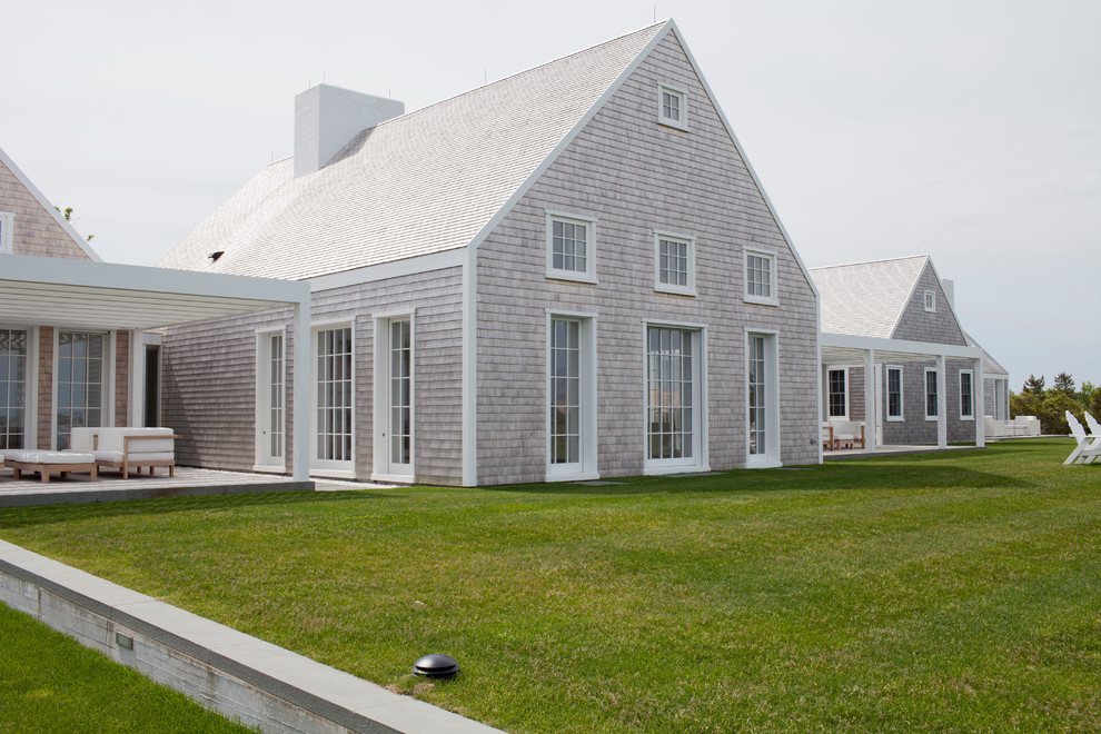 Photo of a large beach style one-storey beige exterior in Boston with wood siding and a gable roof.
