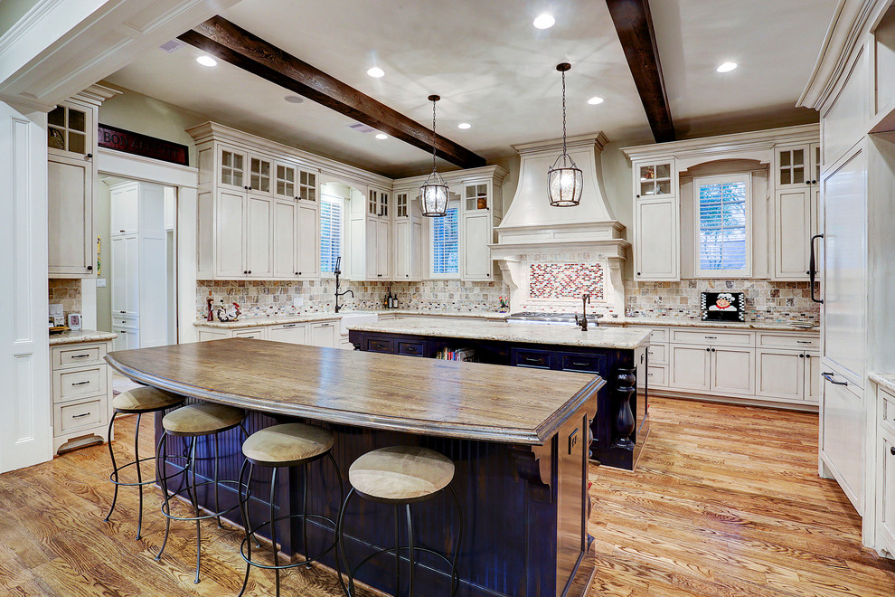 Design ideas for a large traditional kitchen in Houston with a farmhouse sink, shaker cabinets, multi-coloured splashback, panelled appliances, medium hardwood floors, multiple islands, white cabinets, brown floor, beige benchtop and exposed beam.