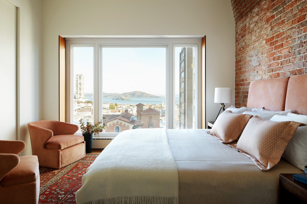 Contemporary bedroom in San Francisco with white walls, medium hardwood floors, brown floor and brick walls.