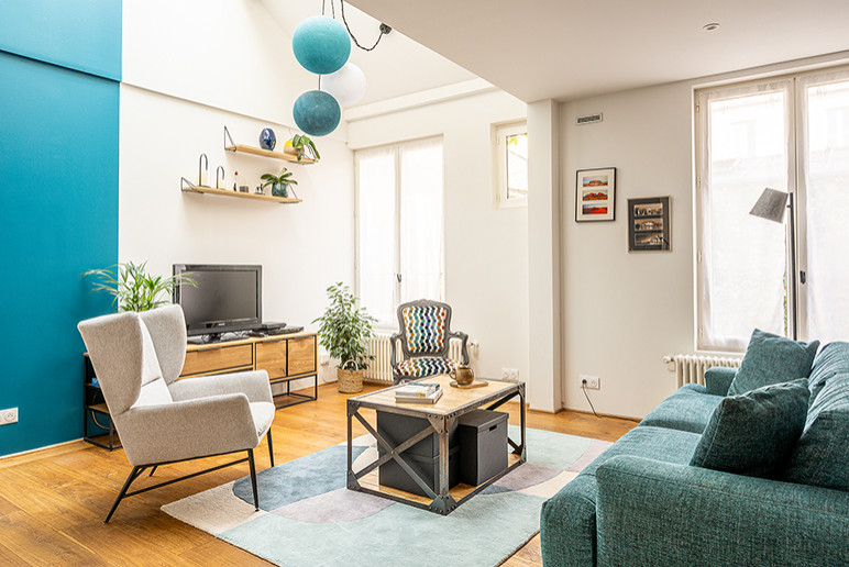 Immagine di un soggiorno bohémian aperto con pareti blu, TV autoportante e pavimento beige