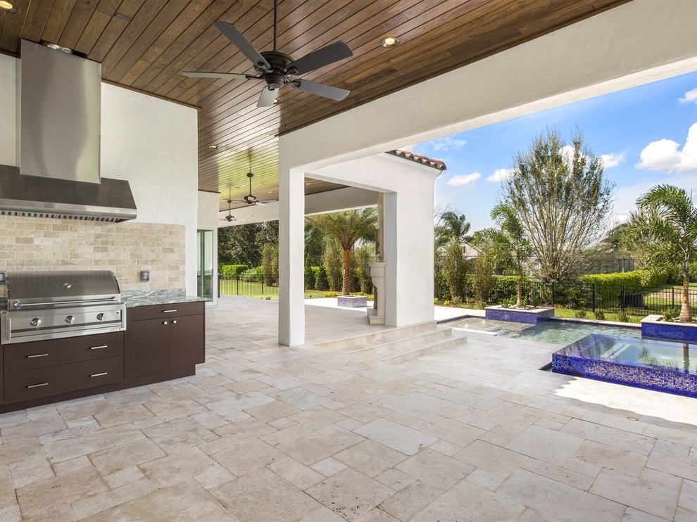 Design ideas for a large mediterranean backyard patio in Orlando with an outdoor kitchen, natural stone pavers and a roof extension.