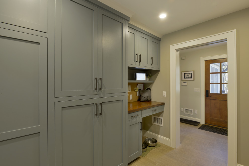 Design ideas for a large transitional mudroom in New York with grey walls, porcelain floors, a single front door, a medium wood front door and beige floor.