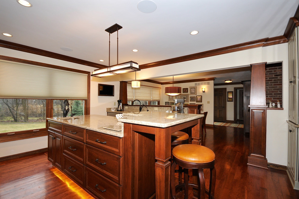 This is an example of a mid-sized arts and crafts single-wall eat-in kitchen in Indianapolis with an undermount sink, recessed-panel cabinets, dark wood cabinets, granite benchtops, multi-coloured splashback, ceramic splashback, white appliances, medium hardwood floors and with island.