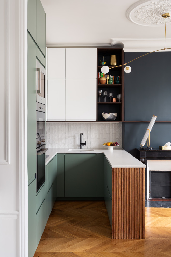 Inspiration for a mid-sized modern u-shaped open plan kitchen in Paris with an integrated sink, beaded inset cabinets, green cabinets, quartzite benchtops, white splashback, marble splashback, stainless steel appliances, medium hardwood floors, with island, white benchtop and wood.