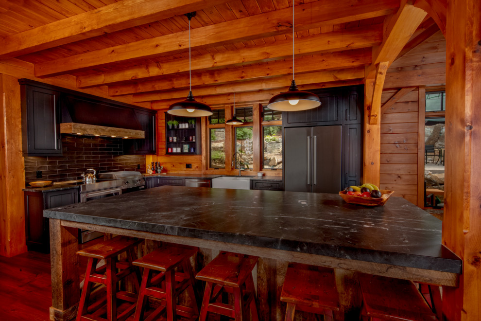 Eat-in kitchen - mid-sized rustic l-shaped medium tone wood floor and brown floor eat-in kitchen idea with a farmhouse sink, shaker cabinets, black cabinets, quartz countertops, black backsplash, stainless steel appliances, an island and black countertops