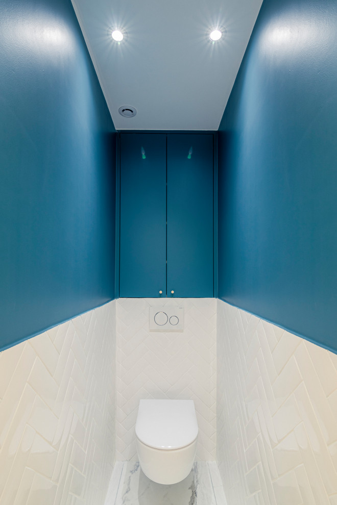 Источник вдохновения для домашнего уюта: туалет среднего размера в современном стиле с фасадами с декоративным кантом, синими фасадами, инсталляцией, белой плиткой, плиткой кабанчик, синими стенами, мраморным полом, белым полом и подвесной тумбой