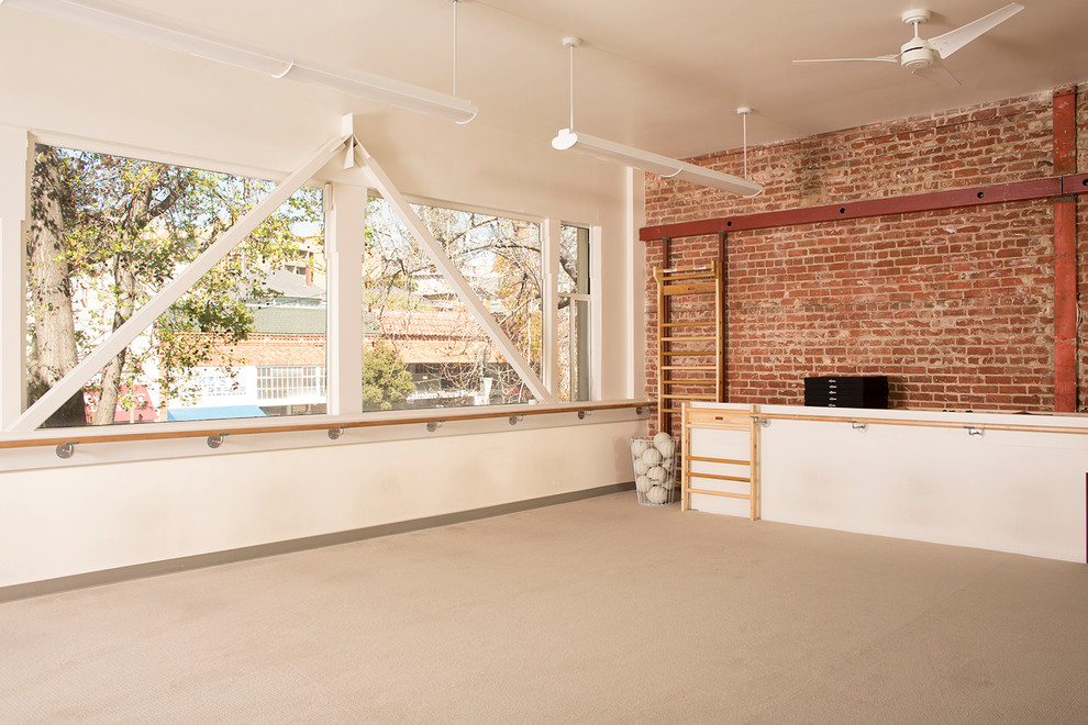 Design ideas for a large industrial home yoga studio with beige walls and carpet.