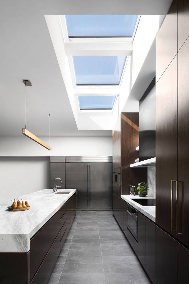 This is an example of a large contemporary l-shaped eat-in kitchen in Melbourne with an undermount sink, flat-panel cabinets, dark wood cabinets, marble benchtops, marble splashback, black appliances, porcelain floors, with island and grey floor.