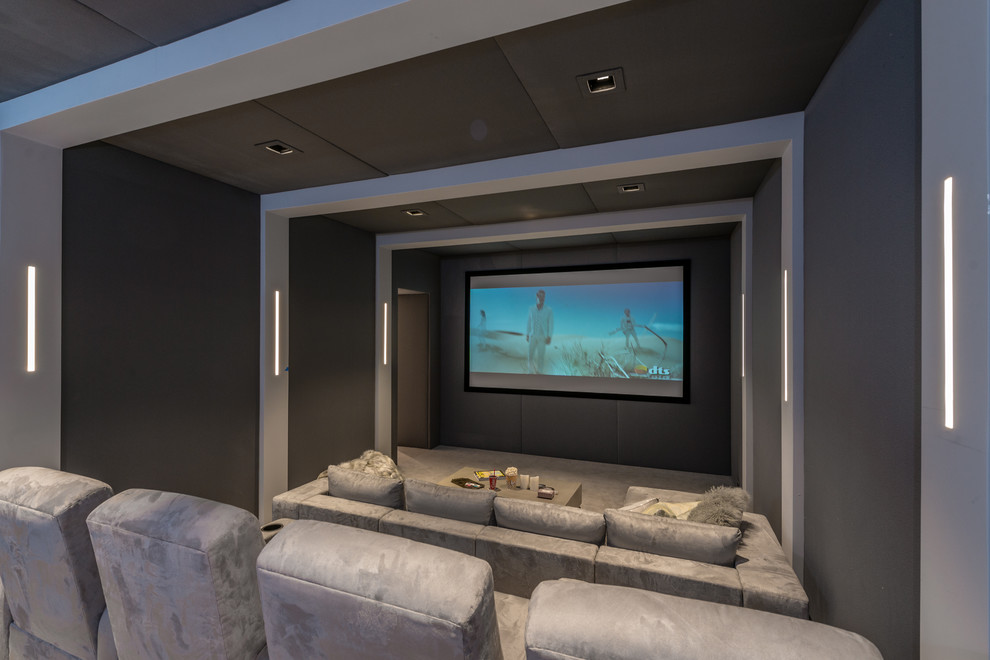 This is an example of an expansive contemporary enclosed home theatre in New York with grey walls, a wall-mounted tv and beige floor.