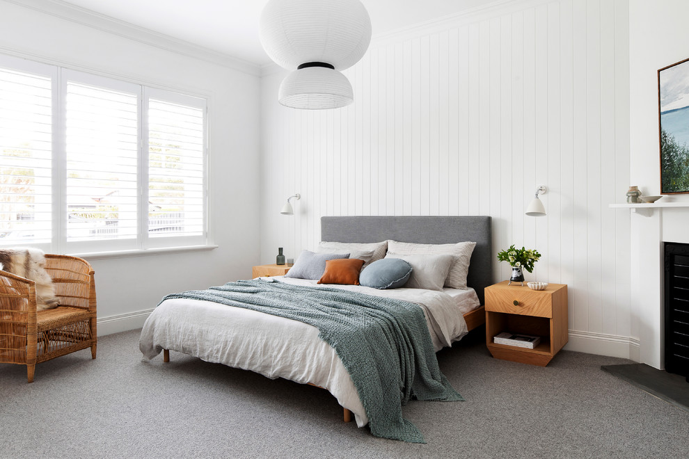 Mid-sized beach style master bedroom in Melbourne with white walls, carpet, a corner fireplace and grey floor.