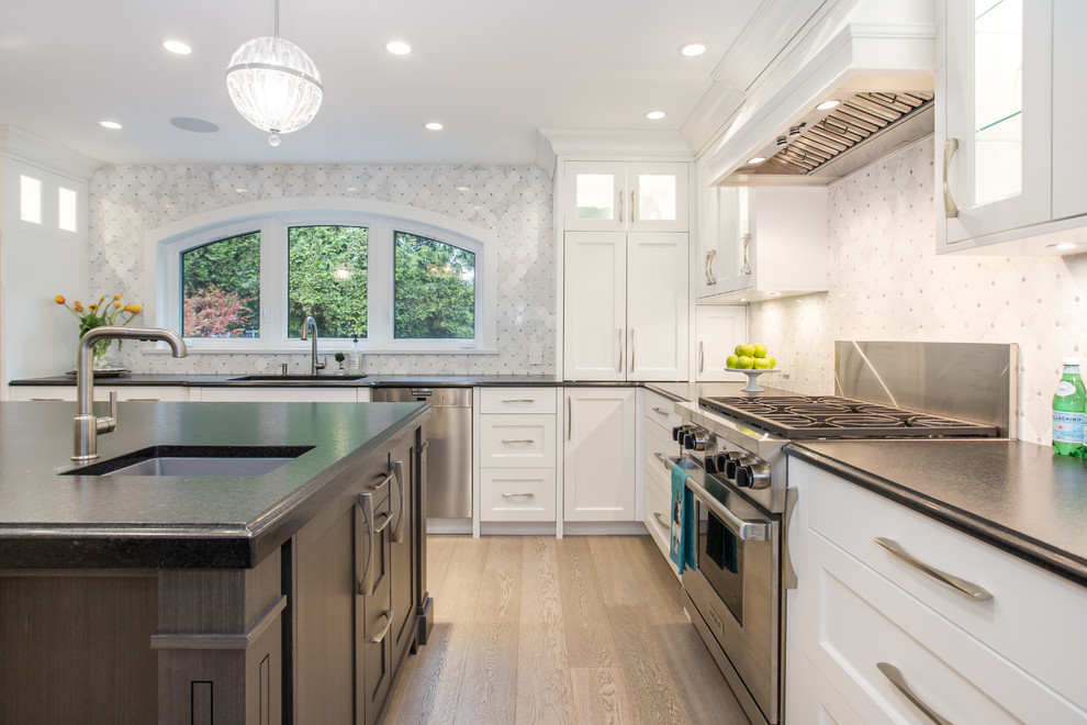 Inspiration for a large transitional l-shaped medium tone wood floor and beige floor eat-in kitchen remodel in Vancouver with an undermount sink, shaker cabinets, white cabinets, granite countertops, gray backsplash, marble backsplash, stainless steel appliances, an island and black countertops