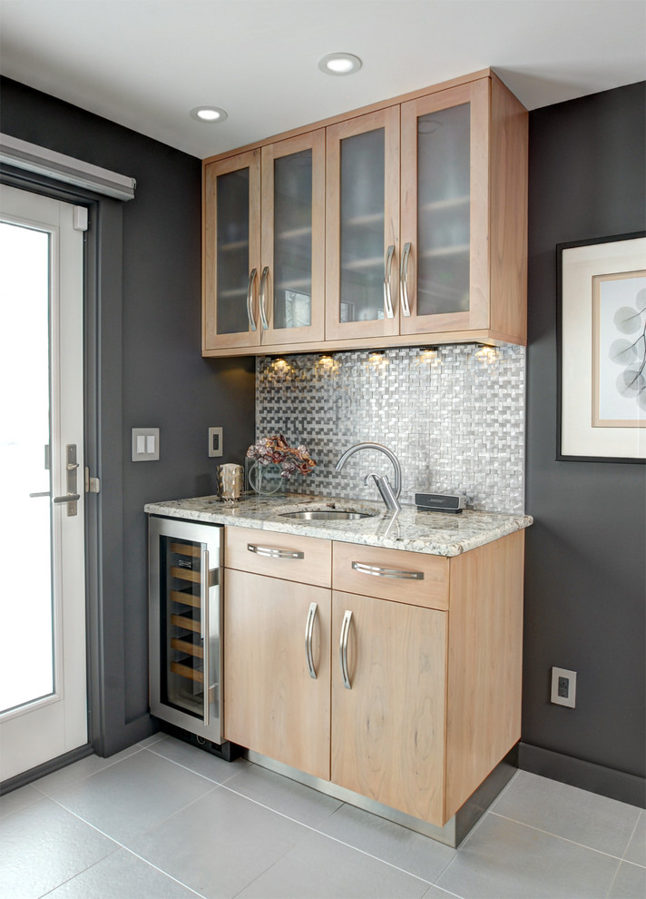 This is an example of a small contemporary single-wall wet bar in New York with an undermount sink, flat-panel cabinets, light wood cabinets, metal splashback and grey floor.