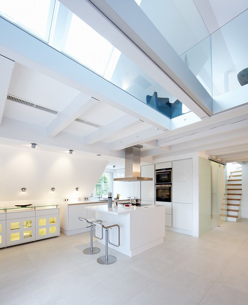 Photo of a mid-sized contemporary l-shaped open plan kitchen in Dortmund with panelled appliances, flat-panel cabinets, white cabinets, with island and beige floor.