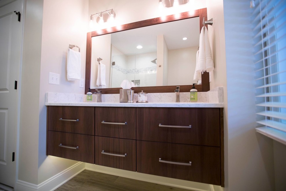 Example of a mid-sized transitional 3/4 gray tile and matchstick tile medium tone wood floor and brown floor corner shower design with flat-panel cabinets, dark wood cabinets, beige walls, an undermount sink, marble countertops and a hinged shower door