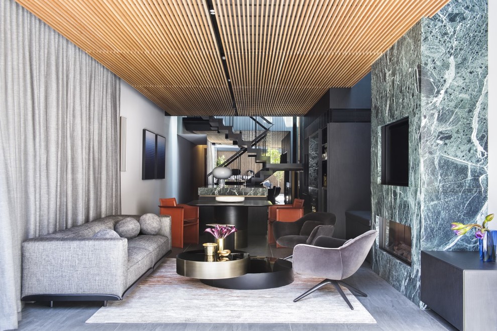 Contemporary open concept family room in Sydney with white walls, a ribbon fireplace, a stone fireplace surround, a wall-mounted tv and grey floor.