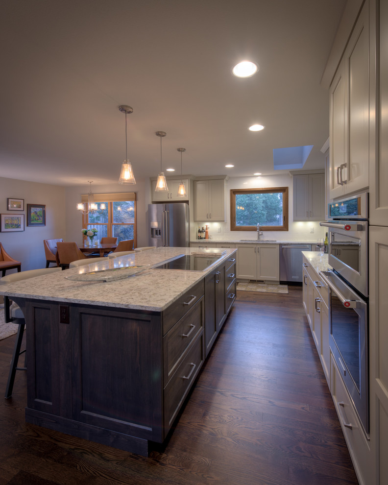 Large transitional dark wood floor kitchen photo in Denver with an undermount sink, shaker cabinets, solid surface countertops, white backsplash, ceramic backsplash, stainless steel appliances and an island