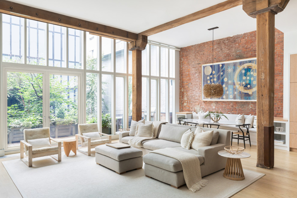 Photo of a large contemporary loft-style living room in New York with white walls, light hardwood floors, no fireplace, a freestanding tv and brown floor.
