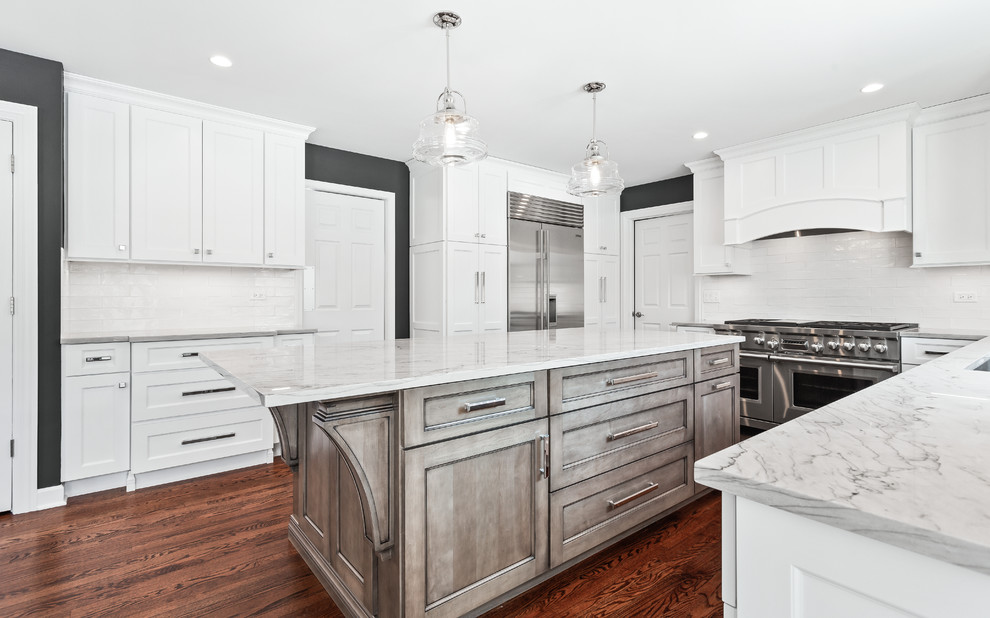 Inspiration for a large transitional u-shaped eat-in kitchen in Chicago with a single-bowl sink, shaker cabinets, white cabinets, quartzite benchtops, white splashback, porcelain splashback, stainless steel appliances, medium hardwood floors, with island, brown floor and grey benchtop.