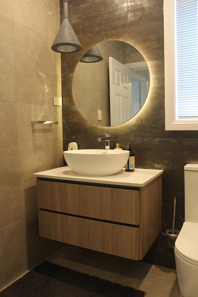 Small contemporary bathroom in Sydney with flat-panel cabinets, medium wood cabinets, an alcove shower, a one-piece toilet, black tile, porcelain tile, grey walls, porcelain floors, a vessel sink, engineered quartz benchtops, grey floor, a hinged shower door and white benchtops.