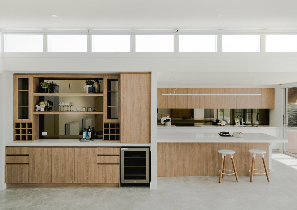 This is an example of a contemporary kitchen in Melbourne with an undermount sink, quartz benchtops, metallic splashback, mirror splashback, stainless steel appliances, porcelain floors, with island, grey floor and white benchtop.