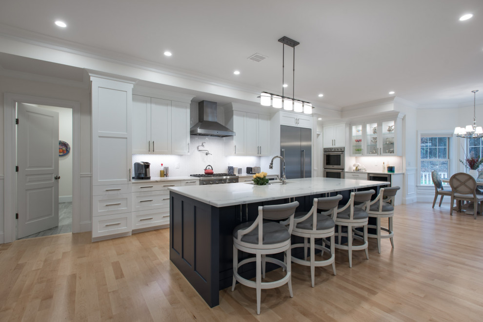 Design ideas for a large transitional kitchen in Boston with an undermount sink, shaker cabinets, white cabinets, quartzite benchtops, white splashback, mosaic tile splashback, stainless steel appliances, light hardwood floors, with island and white benchtop.
