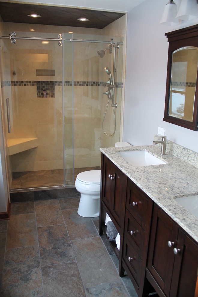 Example of a mid-sized transitional master gray tile and porcelain tile porcelain tile alcove shower design with shaker cabinets, dark wood cabinets, a two-piece toilet, gray walls, an undermount sink and granite countertops