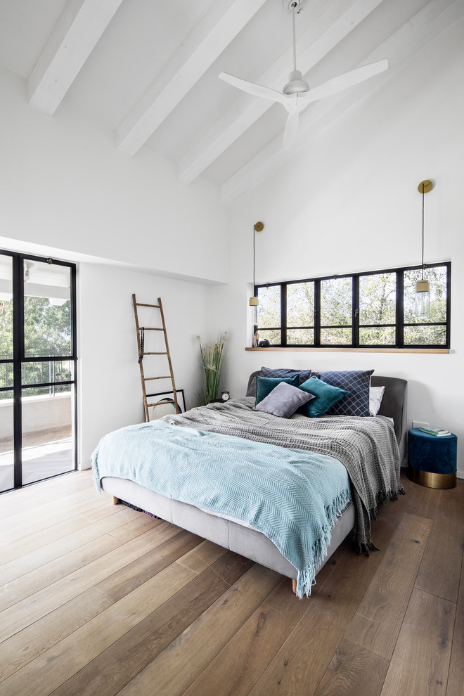 Photo of a scandinavian bedroom in Tel Aviv with white walls, medium hardwood floors and brown floor.