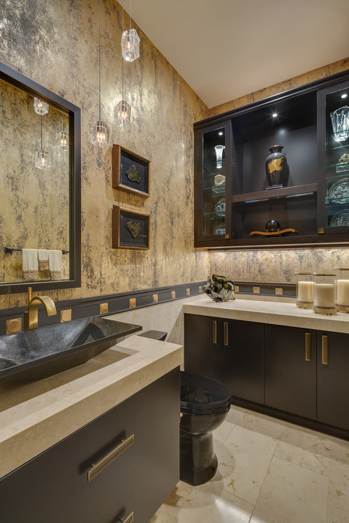 Photo of a mid-sized contemporary powder room in Orange County with furniture-like cabinets, black cabinets, a one-piece toilet, beige tile, limestone, multi-coloured walls, limestone floors, a vessel sink, limestone benchtops, beige floor and beige benchtops.