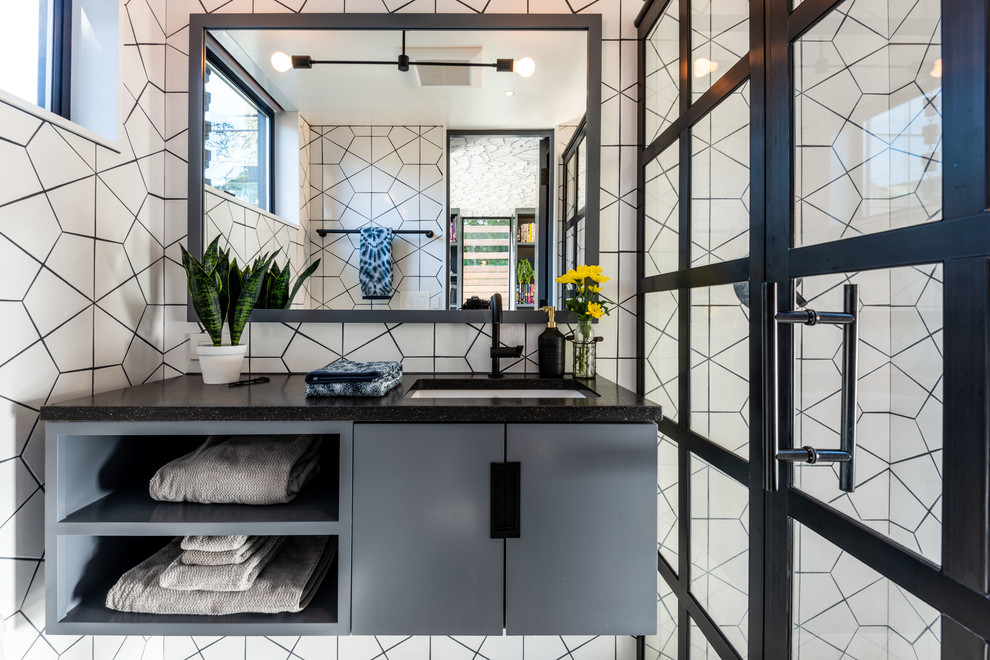 This is an example of a contemporary bathroom in Seattle with flat-panel cabinets, grey cabinets, a corner shower, white tile, white walls, an undermount sink, a hinged shower door and black benchtops.