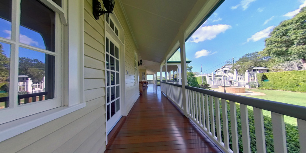 This is an example of a large traditional side yard deck in Brisbane with with privacy feature and a roof extension.