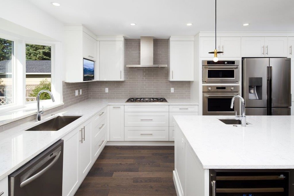 Mid-sized transitional l-shaped dark wood floor and brown floor open concept kitchen photo in Calgary with an undermount sink, shaker cabinets, white cabinets, quartz countertops, gray backsplash, subway tile backsplash, stainless steel appliances and an island