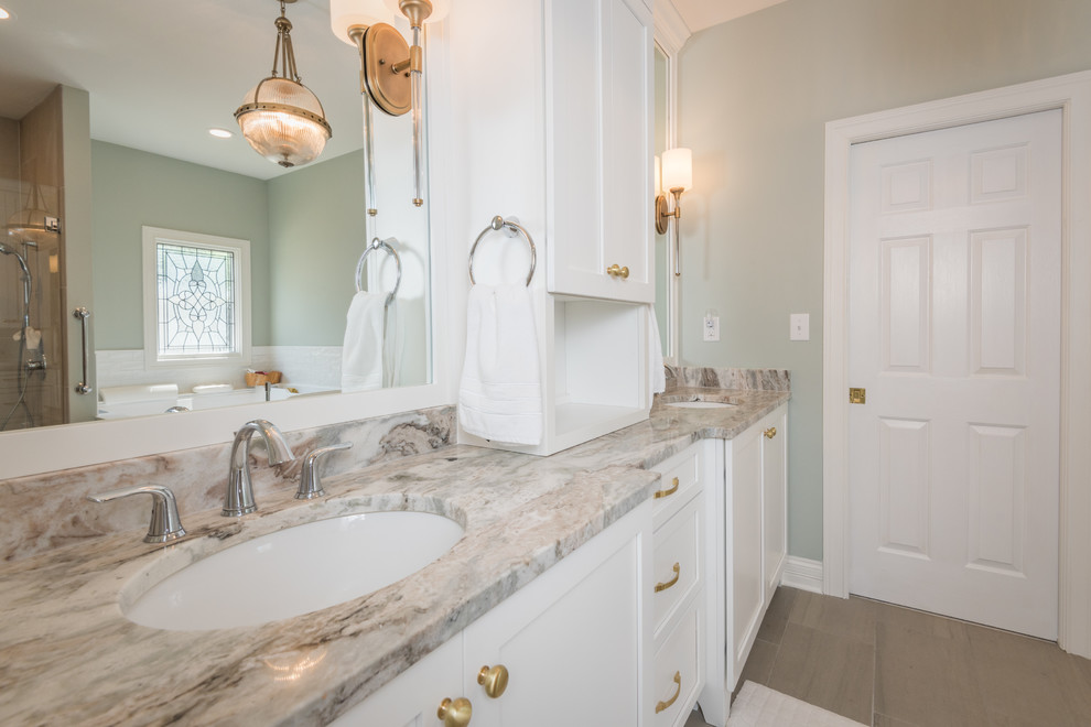 This is an example of a large traditional master bathroom in Louisville with shaker cabinets, white cabinets, an undermount tub, an alcove shower, a one-piece toilet, gray tile, porcelain tile, green walls, porcelain floors, an undermount sink, granite benchtops, grey floor, a hinged shower door and brown benchtops.
