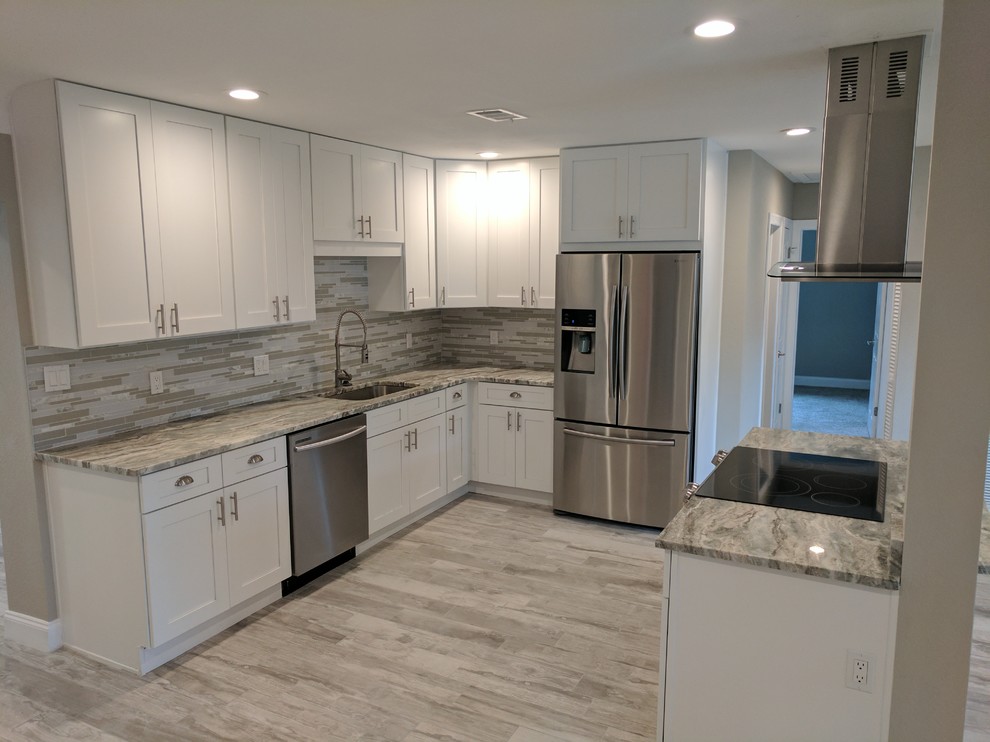 Mid-sized transitional l-shaped light wood floor and gray floor enclosed kitchen photo with an undermount sink, shaker cabinets, white cabinets, granite countertops, multicolored backsplash, matchstick tile backsplash, stainless steel appliances, no island and gray countertops
